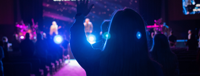 Leading Worship with Compassion | Worshipper with hands raised at a church worship service or other worship event.